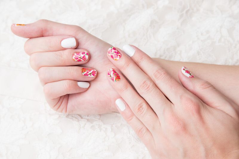 Imagen de uñas blancas con flores rosas.