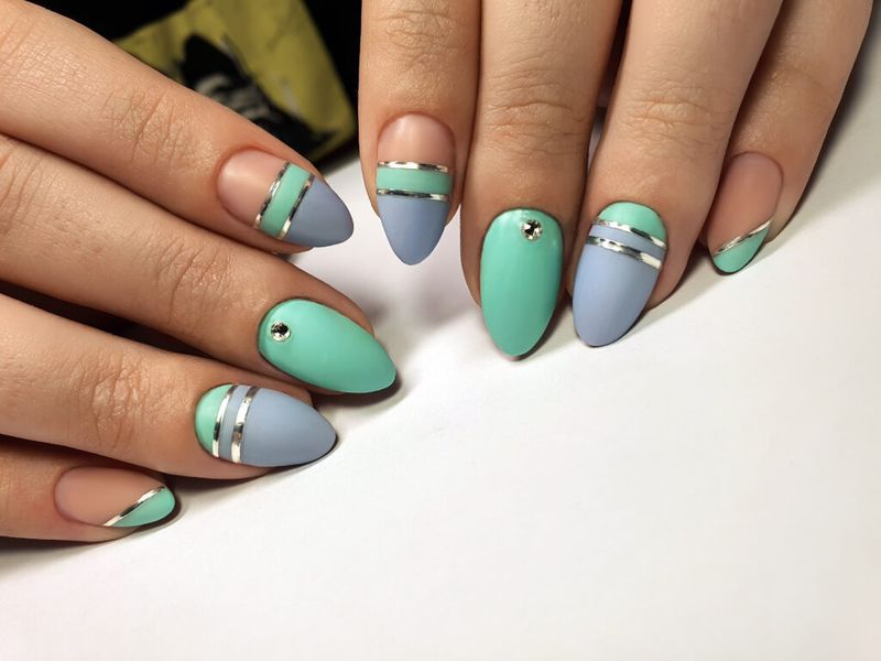 Imagen de uñas azules y verdes con rayas y puntos metalizados.