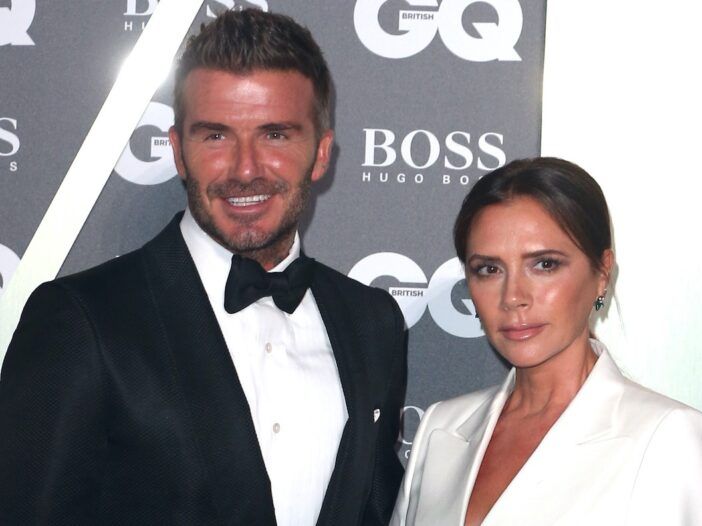 David Beckham hymyilee smokissa vaimonsa Victoria Beckhamin kanssa valkoisessa bleiserissä