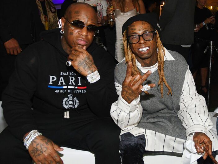 Linnumees, kes kannab musta dressiülikonda, istub koos naeratava Lil Wayne