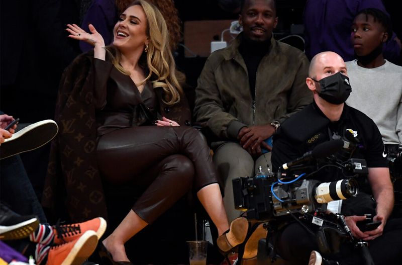Adele sēž laukumā Louis Vuitton mētelī Lakers spēlē ar draugu Riču Polu.