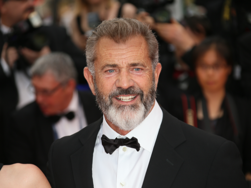 Mel Gibson sonríe en la alfombra roja con un esmoquin negro