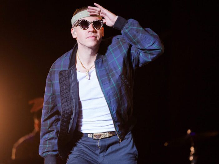 Macklemore actuando en el escenario, con gafas de sol y con la mano sobre la frente como si