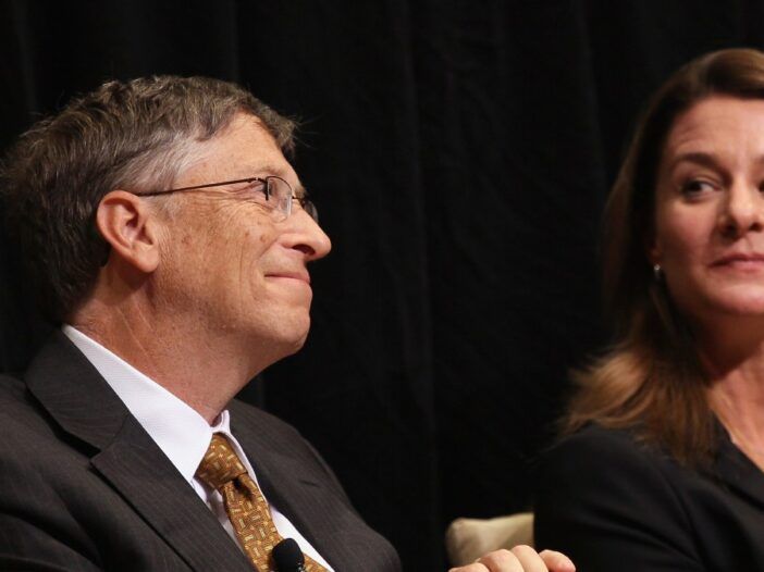 बिल गेट्स मुस्कुराते हैं क्योंकि मेलिंडा गेट्स उनकी ओर देखते हैं जबकि दोनों एक मंच साझा करते हैं
