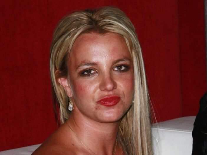 Britney Spears istub valgel diivanil, kandes musta paelteta kleiti