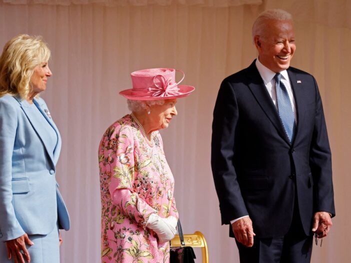 Dr Jill Biden, karalienė Elžbieta ir prezidentas Joe Bidenas stovi kartu ant pakylos