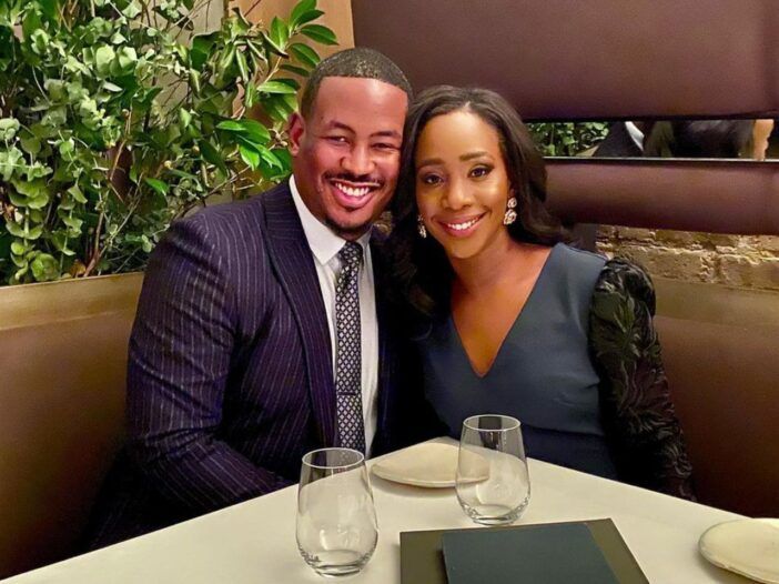 Abby Phillip y su esposo Marcus Richardson sentados en una mesa de cena formal y sonriendo.