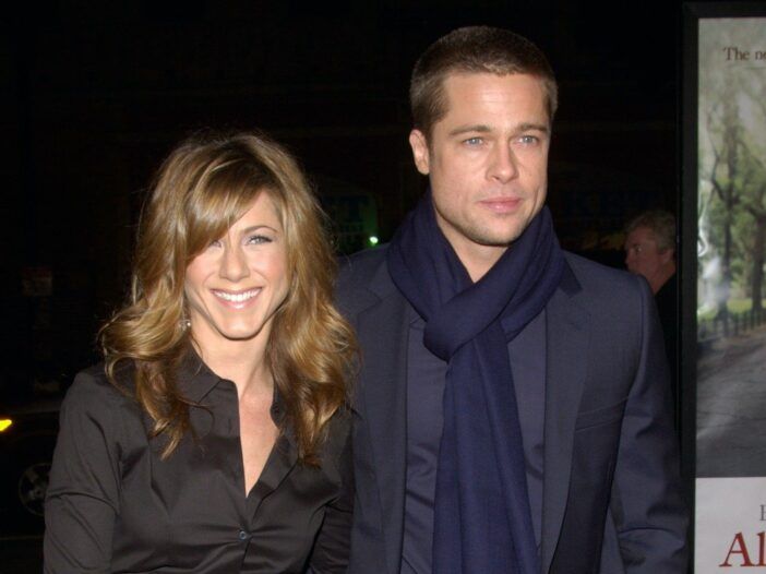 Bradas Pittas vilki tamsiai mėlyną kostiumą ir šaliku, apkabinęs tuometinę žmoną Jennifer Aniston juoda palaidine
