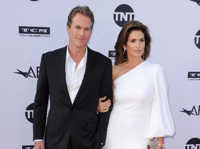 Rande Gerber con un traje negro y posando con su esposa Cindy Crawford, con un vestido blanco.
