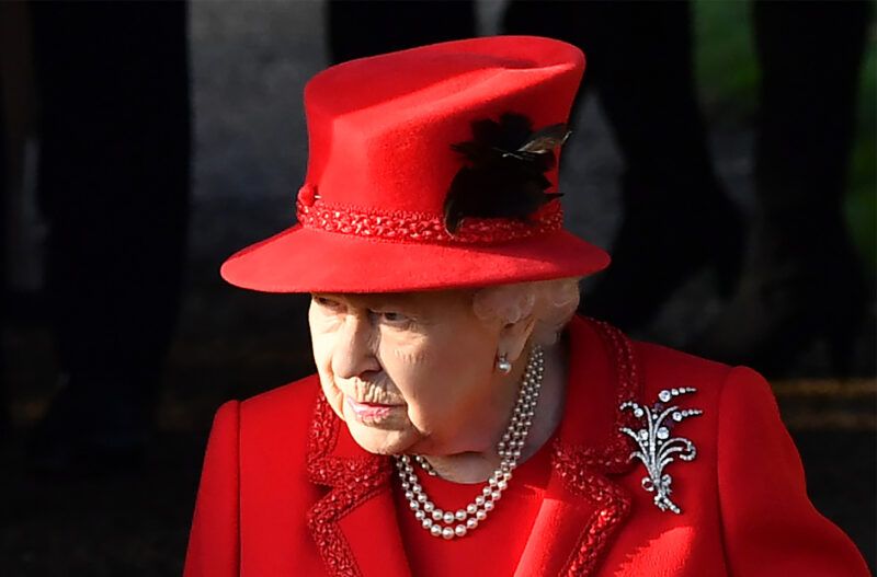 La reina Isabel vestida de rojo, con aspecto severo.