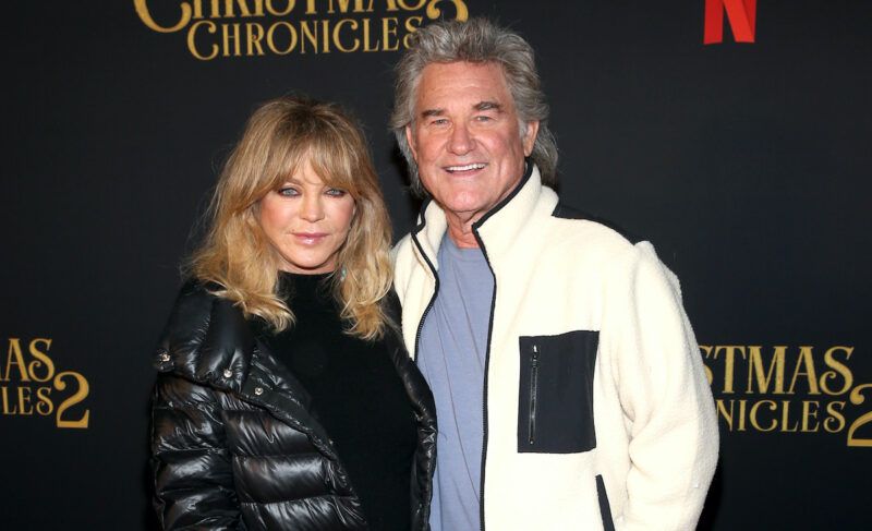 Goldie Hawn con abrigo negro y Kurt Russell con abrigo blanco