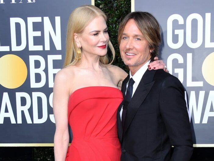 Nicole Kidman raudona suknele šypsosi Keithui Urbanui su kostiumu