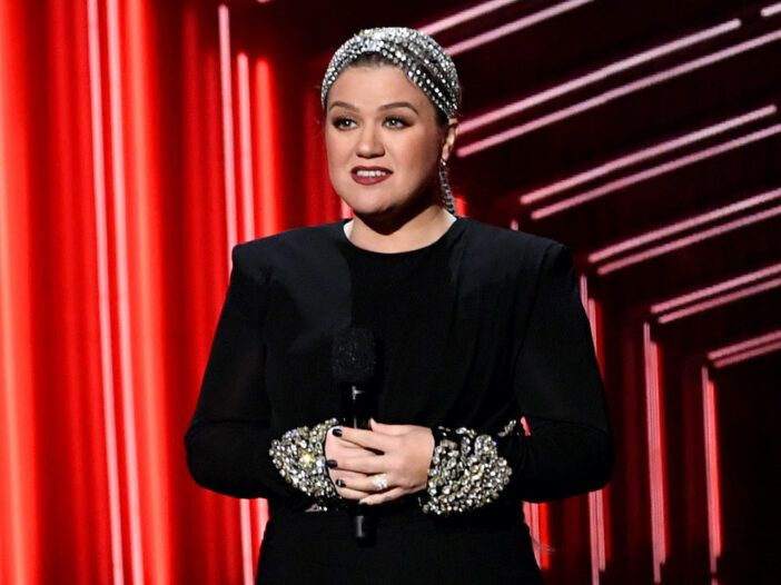 Kelly Clarkson in un vestito nero con in mano un microfono