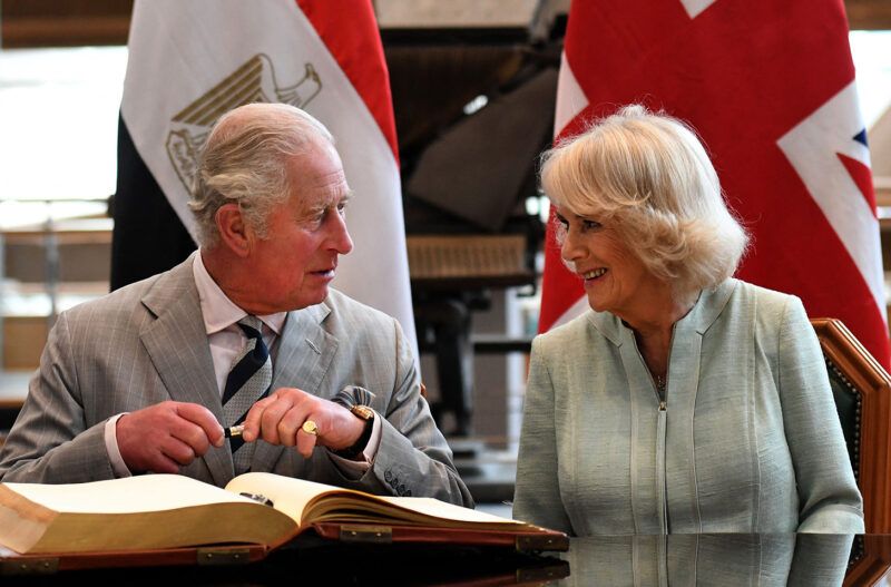 Camilla Parker Bowles y el príncipe Carlos firman un libro de visitas y sonríen