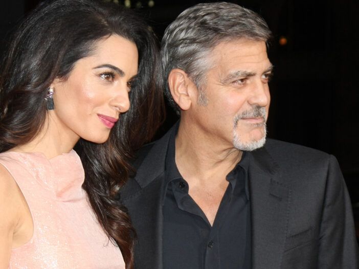 Amal Clooney till vänster i rosa klänning, George Clooney till höger i mörk kostym
