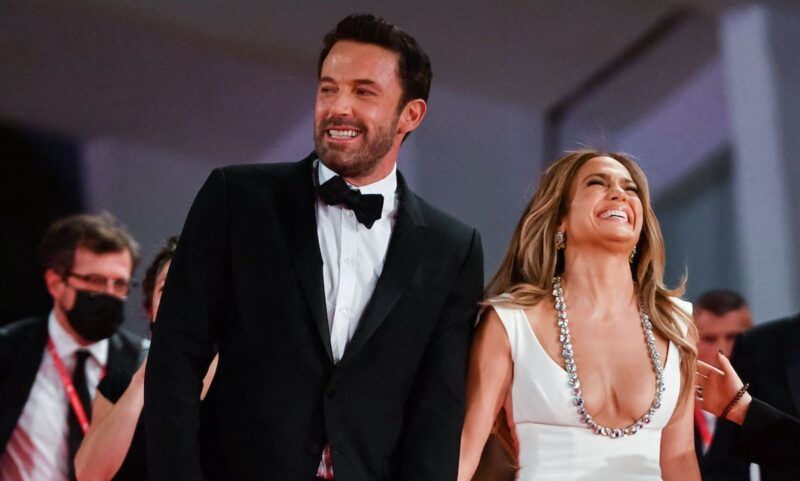 Ben Affleck con esmoquin riéndose con Jennifer López con vestido blanco