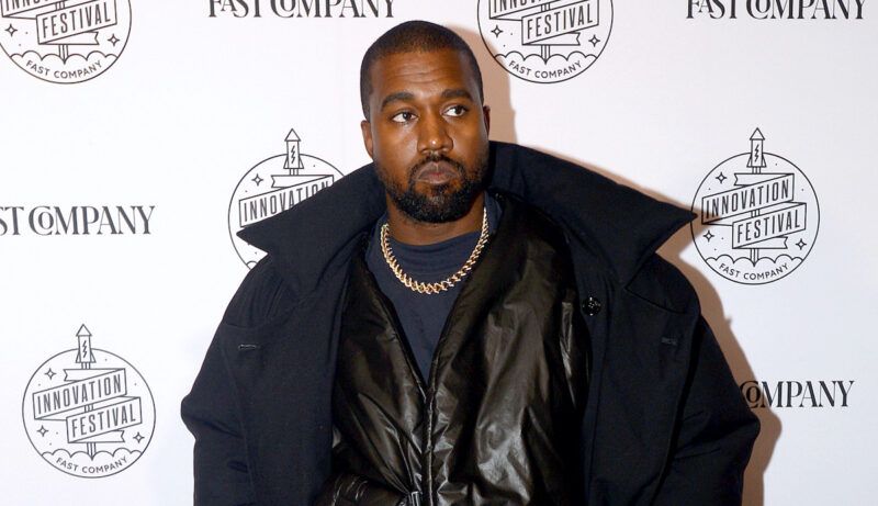 Kanye West con chaleco, camisa, chaqueta y abrigo