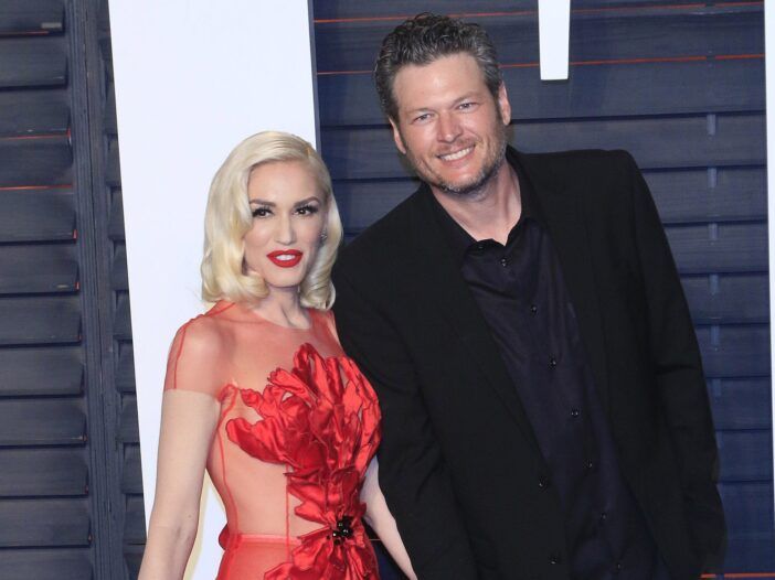 Gwen Stefani v rdeči na levi, Blake Shelton v črni jakni na desni.