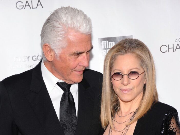 James Brolin mira a Barbra Streisand frente a un fondo blanco.