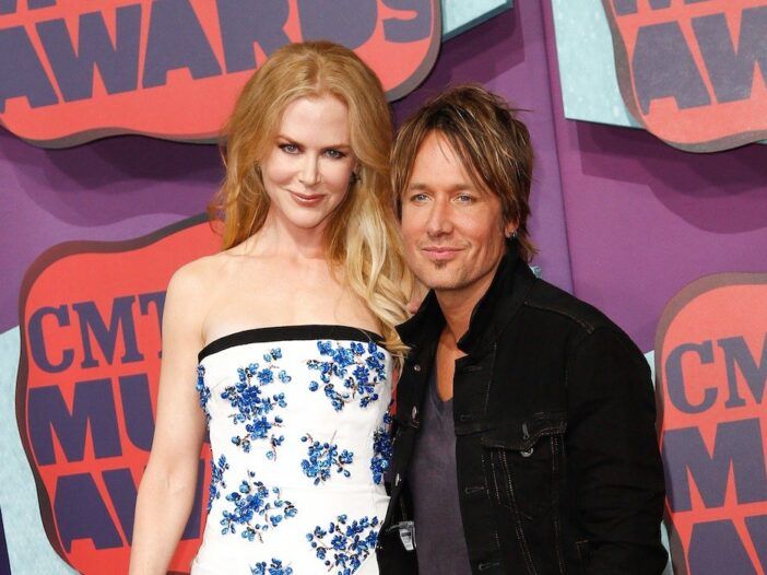 Nicole Kidman con un vestido blanco y azul sonriendo con su esposo Keith Urban en mezclilla