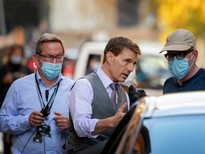 Tom Cruise habla con un hombre con una máscara en el set de la película Misión: Imposible