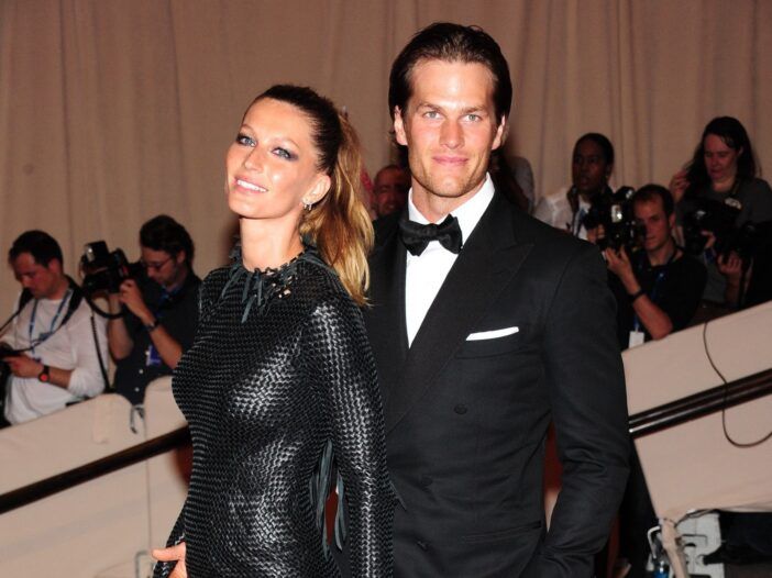 Gisele Bundchen usa un vestido negro y está de pie con su esposo Tom Brady, en un traje negro