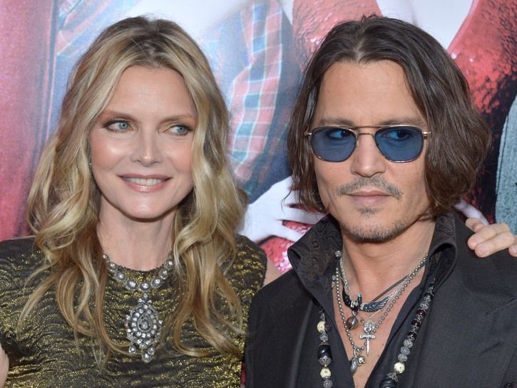 Michelle Pfeiffer con su brazo alrededor de Johnny Depp mientras ambos miran hacia la izquierda.
