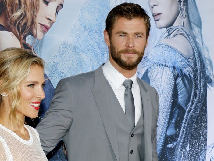 Elsa Pataky, i hvitt, går med Chris Hemsworth, ikledd en grå dress, på den røde løperen