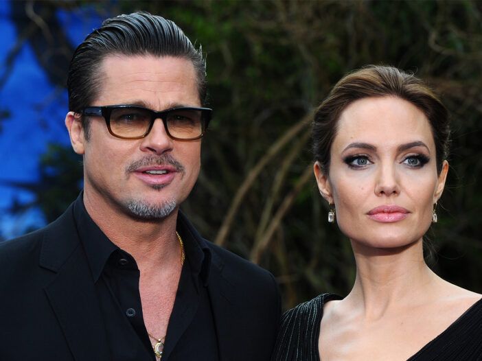 Brad Pitt a la izquierda, con gafas de sol, de pie con Angelina Jolie, luciendo serio.