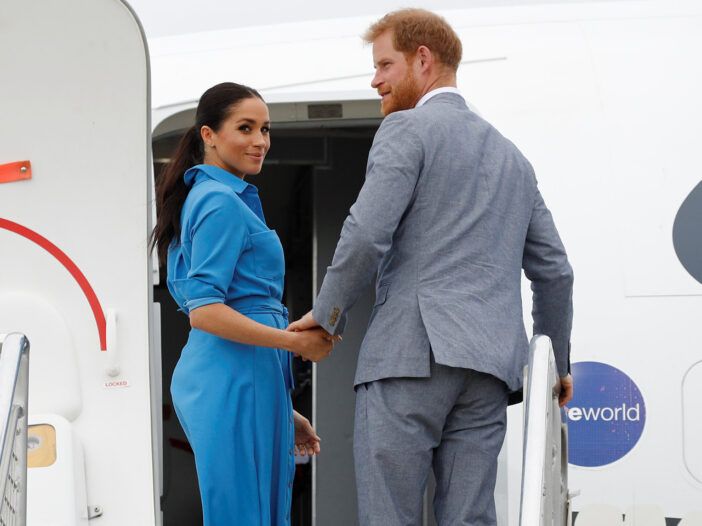 Meghan Markle und Prinz Harry gehen in ein Flugzeug und blicken zurück in die Kameras