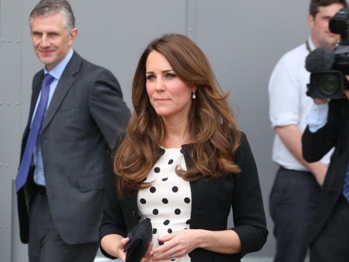 Kate Middleton har på seg en svart genser over en hvit kjole