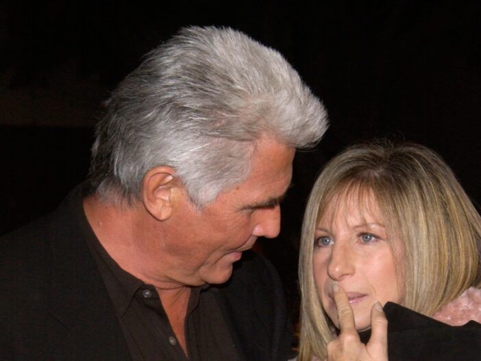 James Brolin se inclina para mirar a Barbra Streisand, quien se lleva un dedo a los labios.