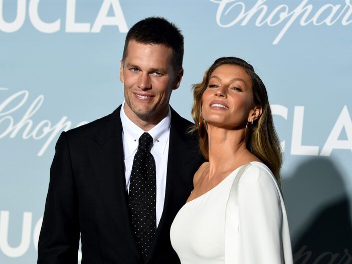 Tom Brady vasakul ülikonnas, Gisele paremal valges kleidis, vaatab dramaatiliselt üles