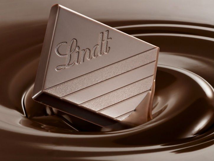 Šķidrās šokolādes baseinā iegremdēts Lindt šokolādes gabals.