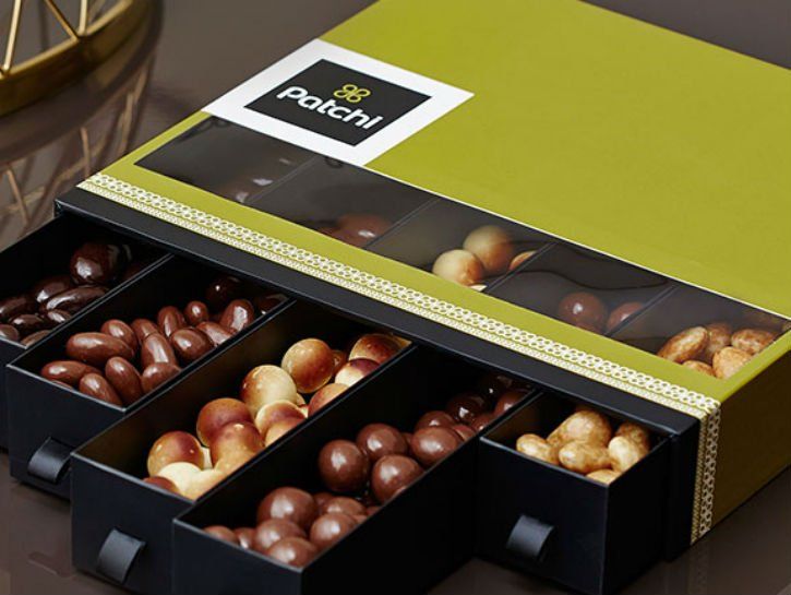 Atidaryta dėžutė su įvairiais Patchi šokoladais ir skanėstais.