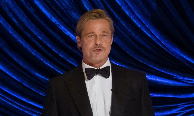 Brad Pitt v smokingu predvádza na pódiu