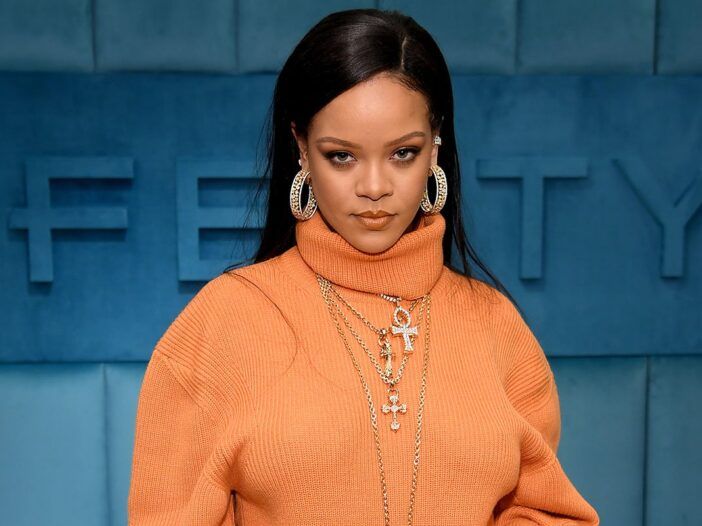Rihanna v oranžnem puloverju gleda v kamero