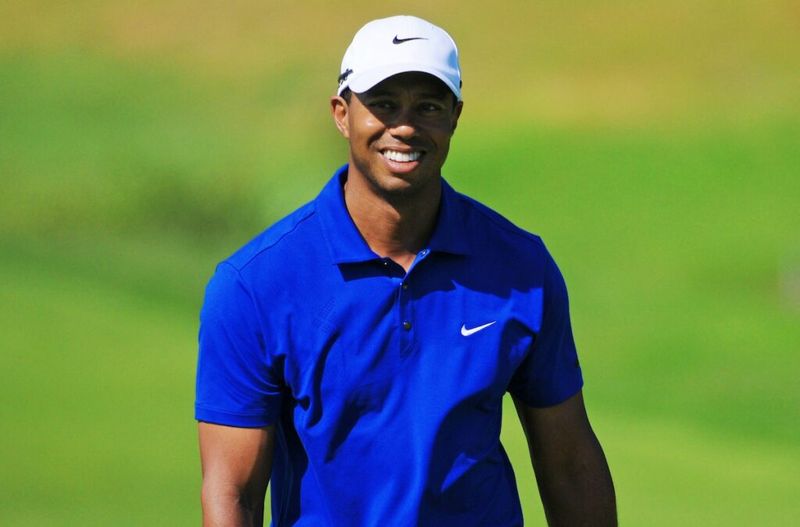 Tiger Woods se smehlja v modrem polo in belem klobuku