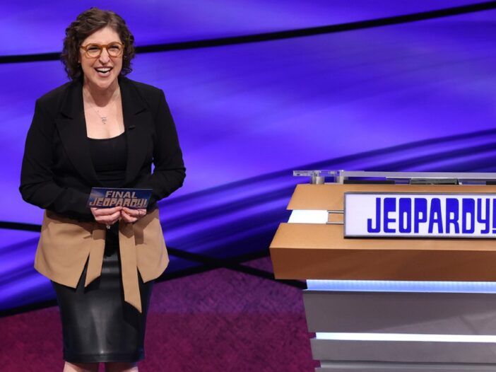 Mayim Bialik naerab Jeopardy võtteplatsil tühja poodiumi kõrval