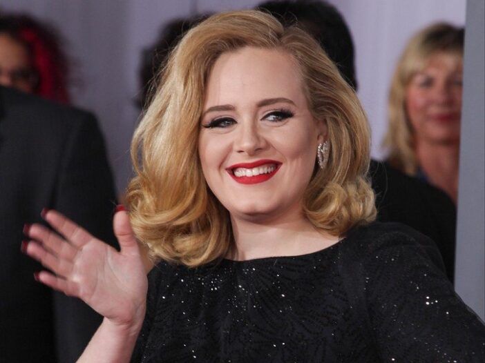 Adele, oblečena v črno obleko, pomaha fotografom na premieri Kong Skull Island