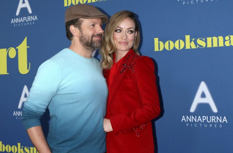 Jason Sudeikis, i blå skjorte, poserer sammen med Olivia Wilde, i rød dress, på premieren til Booksmart
