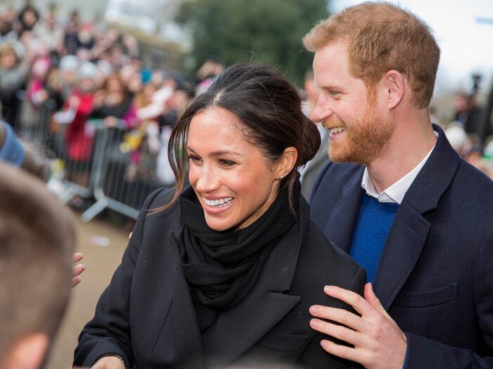 Meghan Markle pozdravlja oboževalce na javnem dogodku s princem Harryjem za njo.