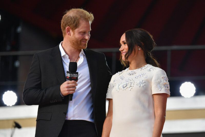 Mustas ülikonnas prints Harry naeratab koos valges kleidis Meghan Markle