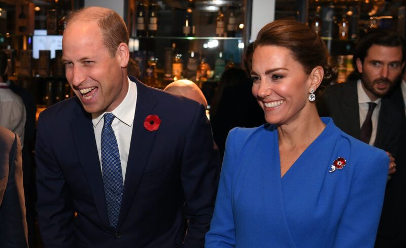 Princas Williamas mėlynu kostiumu juokiasi su Kate Middleton mėlyna spalva