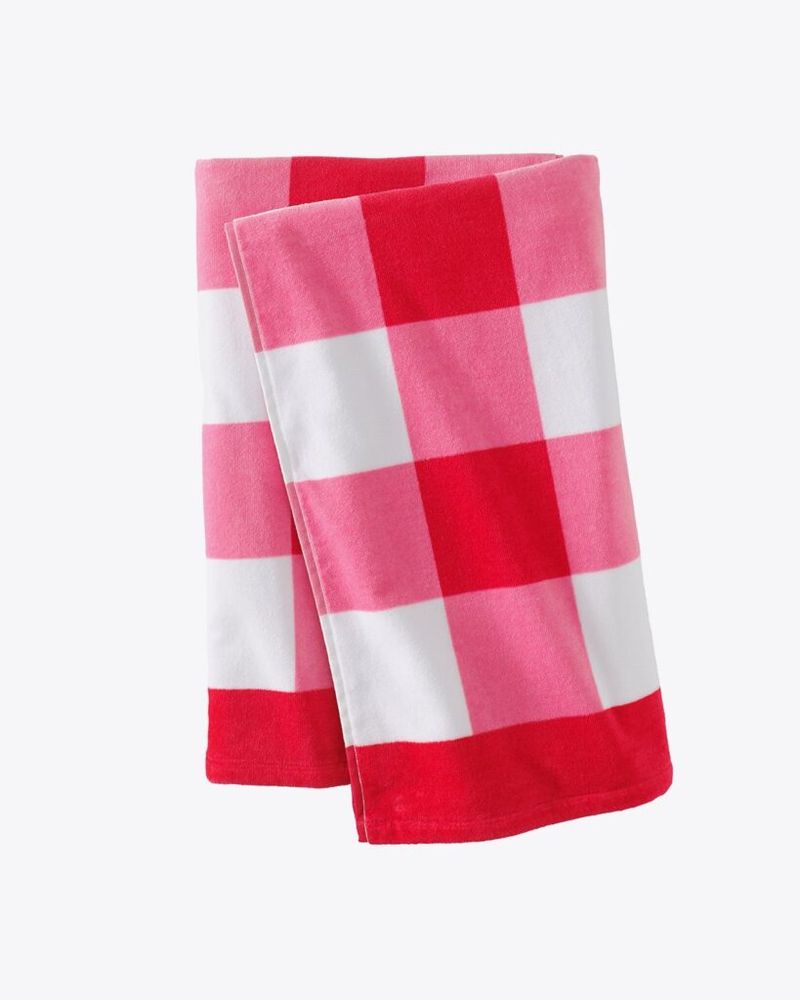 Foto de producto de una toalla de playa en cuadros rojos, rosas y blancos.