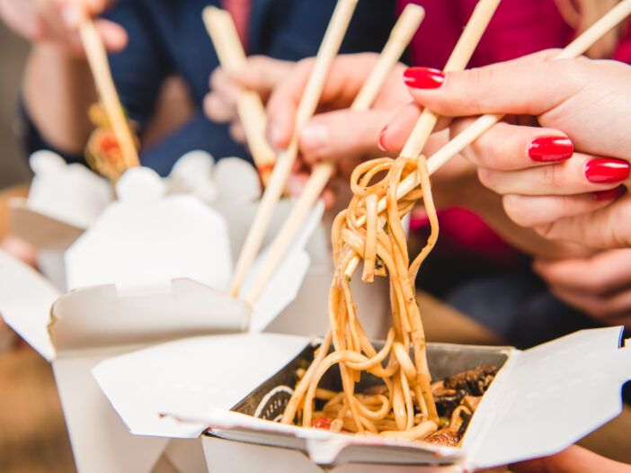 Bilde av kinesisk mat mens folk henter maten med spisepinner.