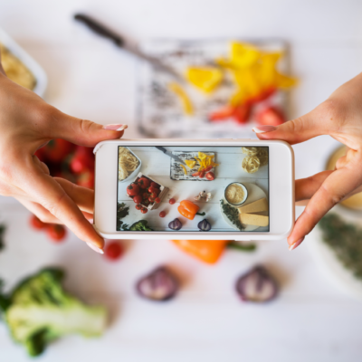 Concepto de blogger de comida. Mujer joven grabando video en un smartphone en la cocina. Mujer grabando cada paso del proceso de cocción para su blog. Dieta, tecnología, salud, alimentación, cocina, culinaria y personas.
