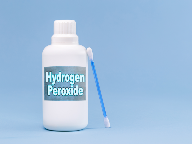 flaske med hydrogenperoksid på blå bakgrunn