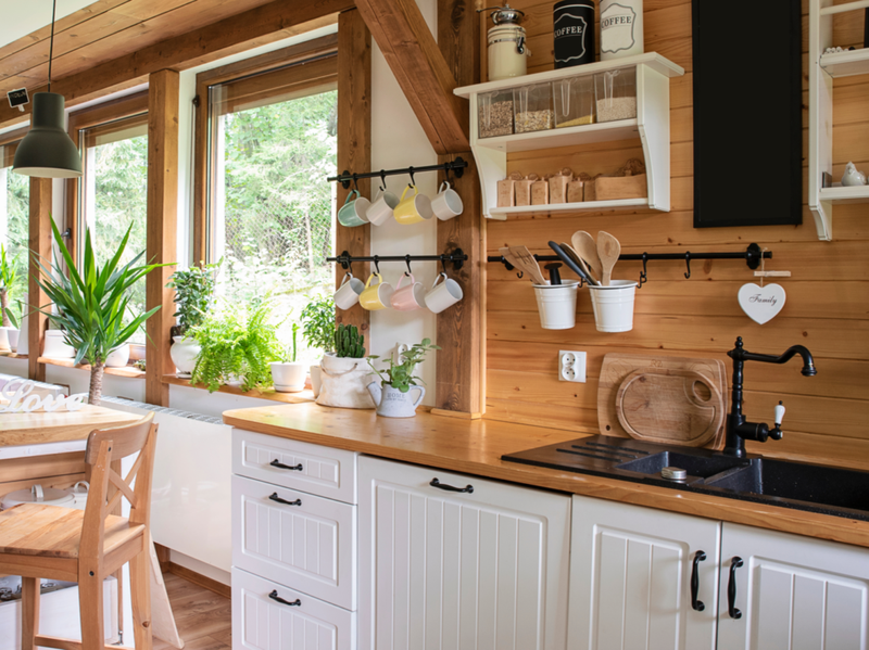 Interior de cocina de estilo rústico con utensilios de cocina vintage y ventana. Muebles blancos y decoración de madera en interiores luminosos.