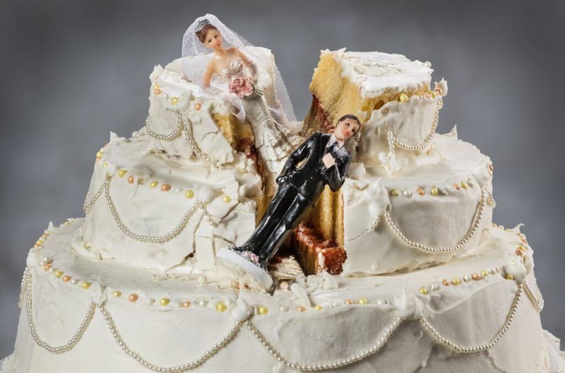 Tort de nuntă zdrobit cu figurine de mire și mireasă